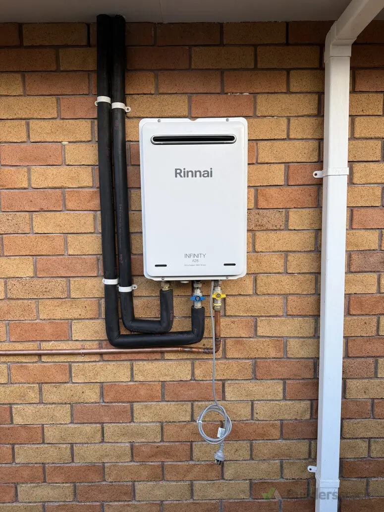 Rinnai Infinity unit on a brick wall with new gas and water connections, installed by Tron Plumbing