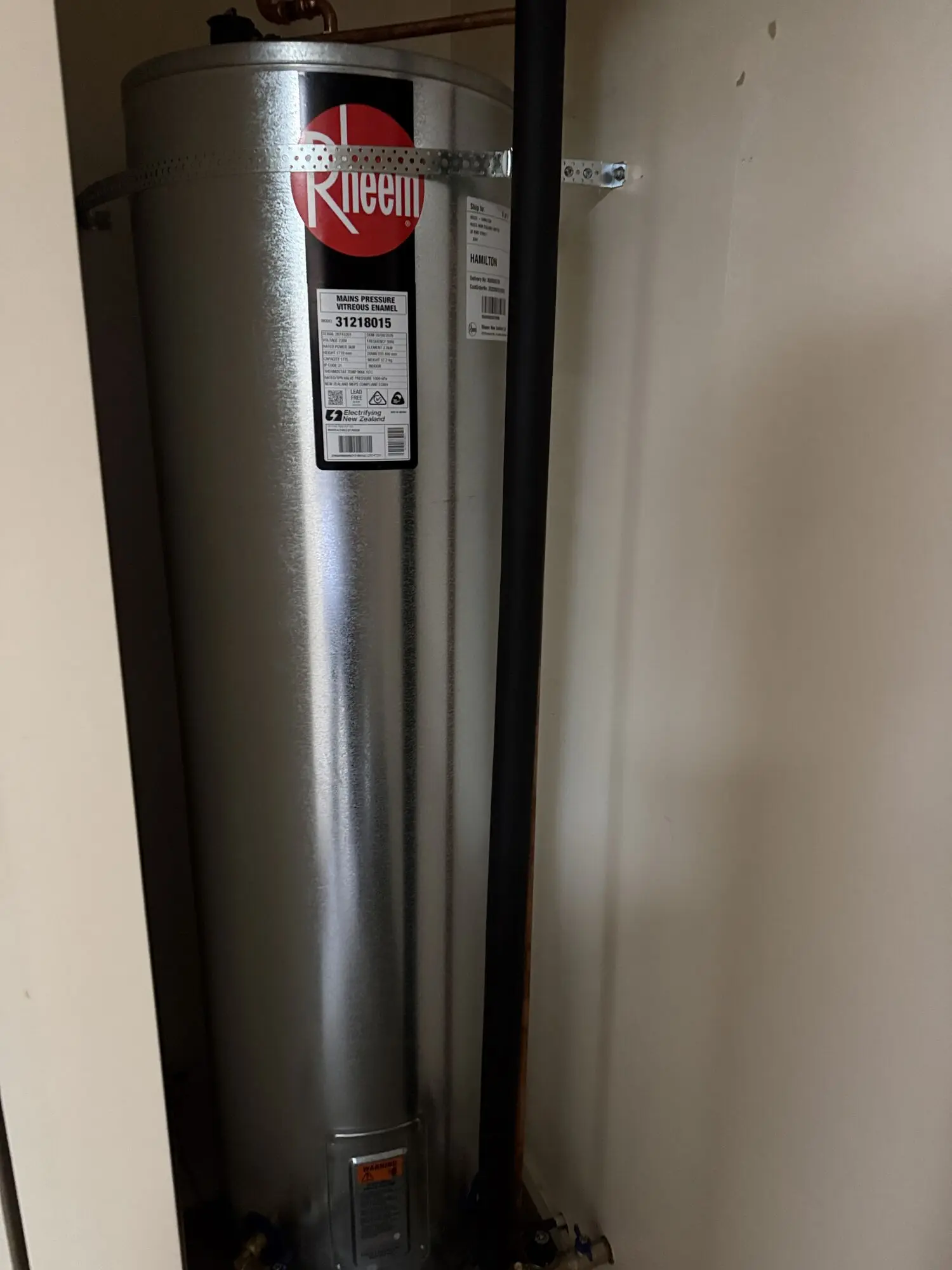 New Rheem mains-pressure cylinder we fitted in a cupboard, still wearing its delivery labels