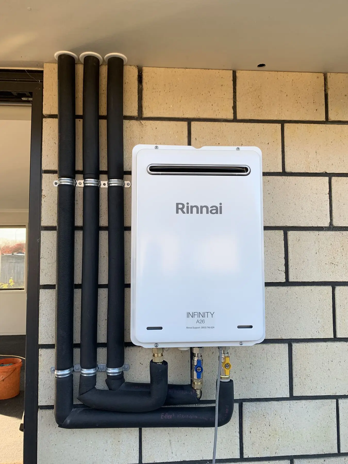 Rinnai Infinity continuous-flow unit installed on a block wall in Hamilton