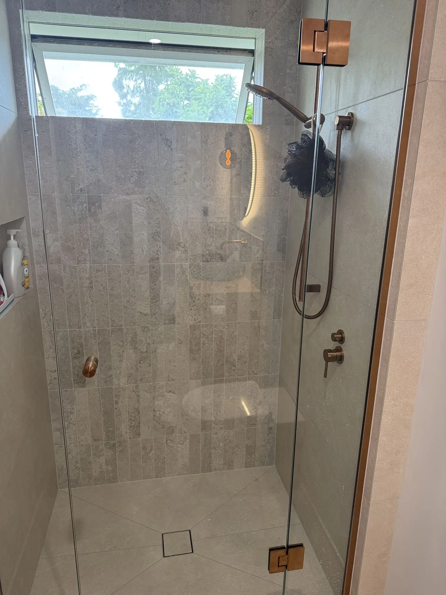 Walk-in shower with copper fittings and a frameless glass screen, plumbed by Tron Plumbing